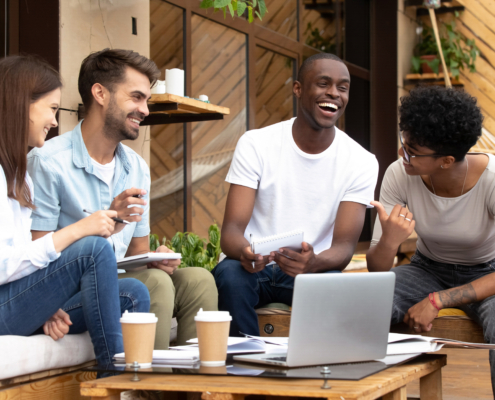 Smiling diverse millennial friends have fun studying in cafe